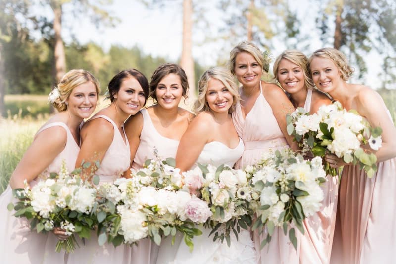 The bride and bridesmaids holding blush wedding flowers.