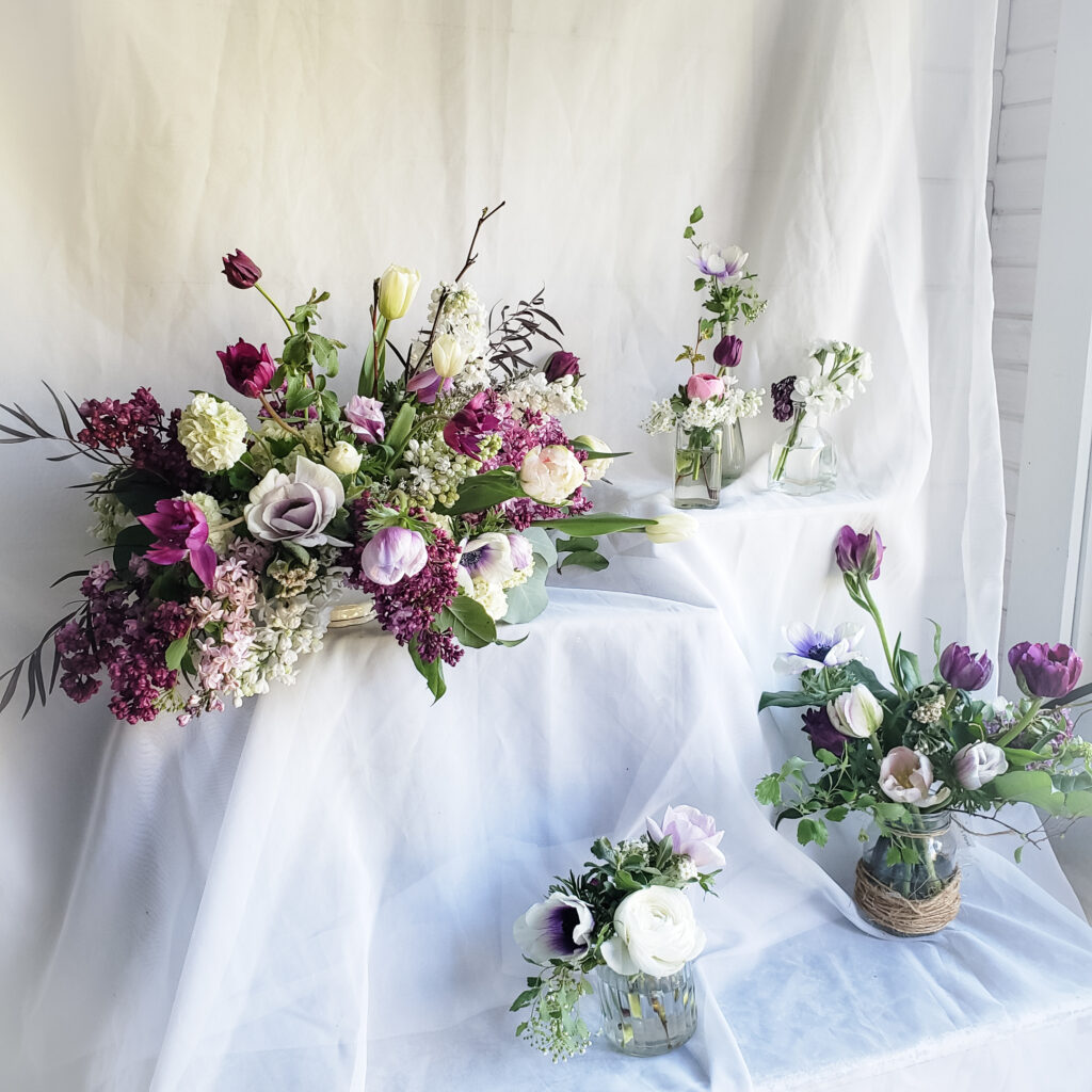 Five plum and white flower arrangements in different sizes.